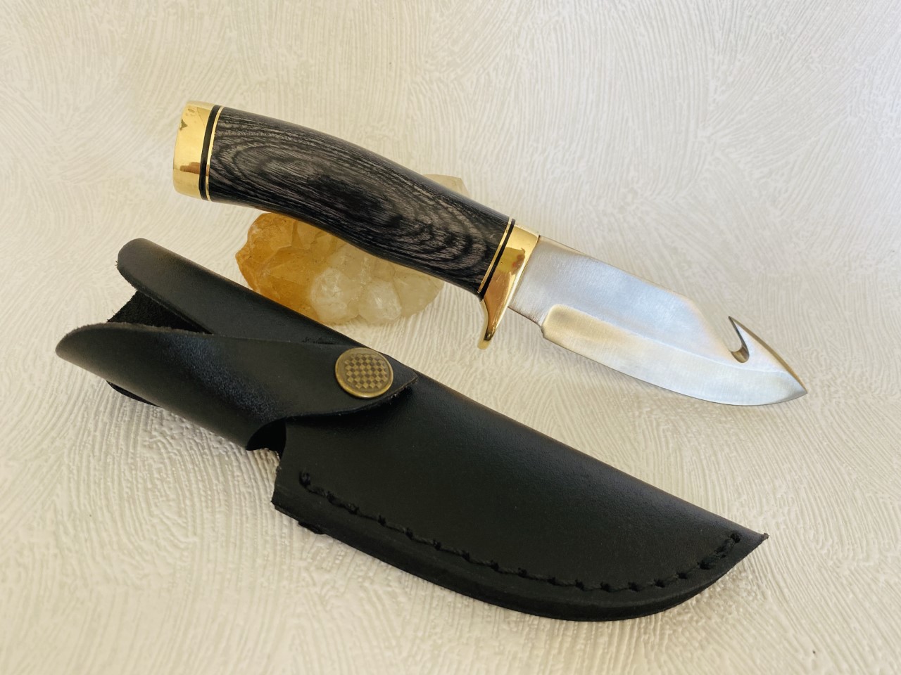 Couteau à dépecer de 22 cm avec son manche en bois coloré noir et son étui au prix de 24,90 euros .
